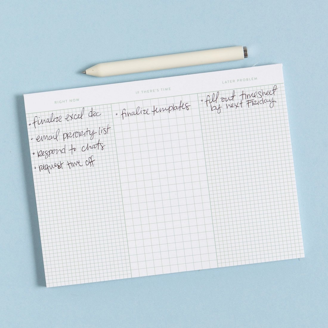 To Do List Grid Notepad open on blue background showing Right Now, If There's Time, and Later Problem columns filled in with handwritten tasks, cream pen resting on top